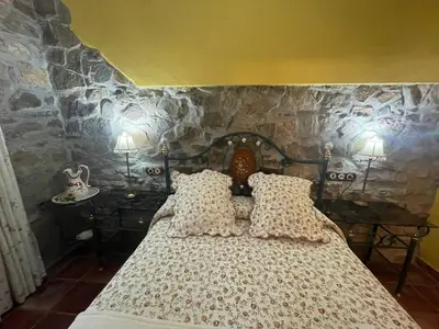 a bedroom with a bed with a stone wall at Apartamentos Torre Villar in Villar de Vildas
