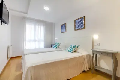 two beds in a room with a table and a television at Duerming Family Viveiro 4 Rooms in Viveiro