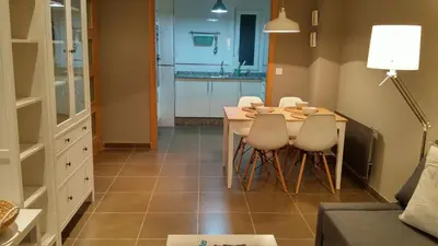 a dining room with a table and chairs and a kitchen at Apartamento con piscina en Foz in Foz