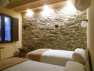a bedroom with two beds and a stone wall at XARDÍN DE ESTRELAS *** in Sarria