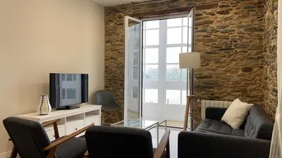 a living room with a couch and a tv at Noray Apartamentos Viveiro in Viveiro
