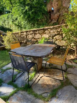 a table with four chairs and a stone wall at Casa de Anamá in Entrecinsa