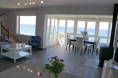 a living room with a table and chairs and the ocean at Playa Catedrales Village in Barreiros