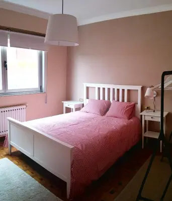 a bedroom with a bed with pink sheets and a window at Amplio apartamento a 5 minutos del centro in Lugo