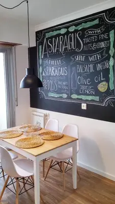 a dining room table with chairs and a chalkboard on the wall at Amplio apartamento a 5 minutos del centro in Lugo