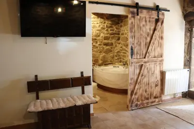 a bathroom with a tub and a shower with a sliding door at Apartamentos Casa do Bouza Vello in Sober