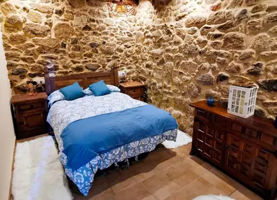 a bedroom with a bed and a stone wall at Apartamentos Casa do Bouza Vello in Sober