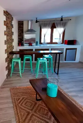 a living room with a table and some green stools at Apartamentos Casa do Bouza Vello in Sober