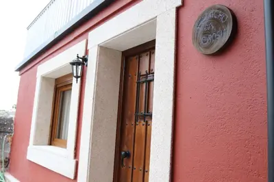 a red building with a door and a sign on it at Apartamentos Casa do Bouza Vello in Sober