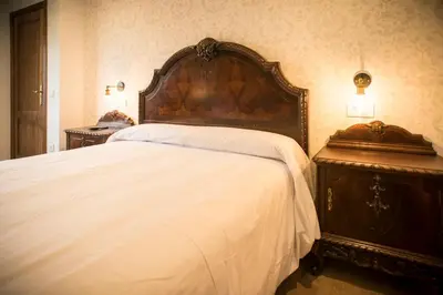 a large bed with a wooden headboard in a bedroom at Hotel portico in Fonsagrada