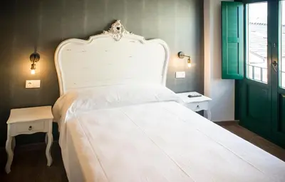 a bedroom with a large white bed with a green door at Hotel portico in Fonsagrada