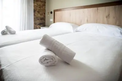 a rolled up towel sitting on top of a bed at Hotel portico in Fonsagrada