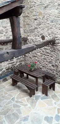 a wooden picnic table with flowers on it next to a stone wall at Casa rural Nica in Arganza