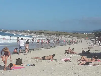 a group of people laying on the beach at Apartamentos Turísticos Rosa in Ribadeo