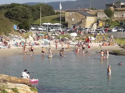a group of people on a beach in the water at Apartamentos Turísticos Rosa in Ribadeo
