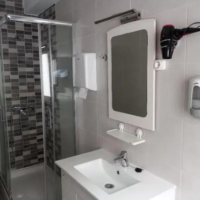 a bathroom with a sink and a mirror and a shower at Pensión Fornos in Caldas de Reis
