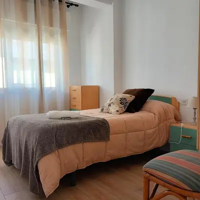 a bedroom with two beds and a chair in it at Pensión Fornos in Caldas de Reis