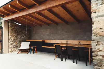 a patio with a wooden table and black chairs at La Isla de Próspero in Tapia de Casariego