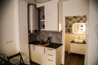 a kitchen with white cabinets and a sink and a mirror at Apartamentos Dacosta in Ribadeo