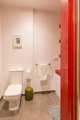 a bathroom with a toilet and a green stool at Apartamento Rosaleda in Melide