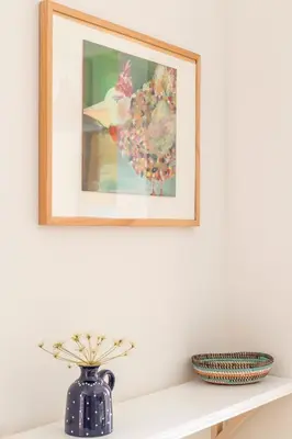 a painting on a white wall above a shelf with a vase at Apartamento Rosaleda in Melide
