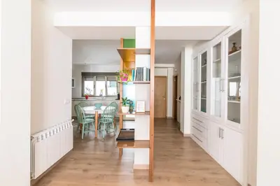 a kitchen and dining room with white cabinets and a table at Apartamento Rosaleda in Melide