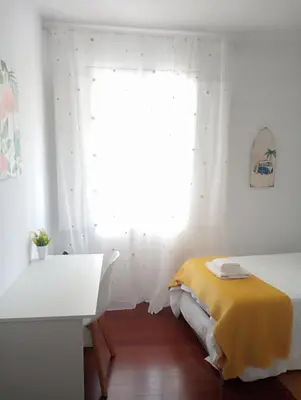 a bedroom with a bed and a desk and a window at Apartamentos CASA AMELIA in Padrón