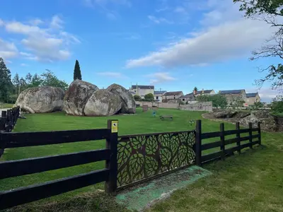 a fence in a field with large rocks at Casa Cástor O Valadouro Galicia in Alaje