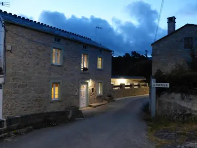a stone house with a street sign in front of it at Casa Cástor O Valadouro Galicia in Alaje