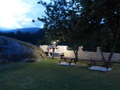 two benches sitting in the grass in a park at Casa Cástor O Valadouro Galicia in Alaje