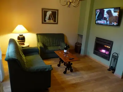 a living room with couches and a table and a tv at Casa Cástor O Valadouro Galicia in Alaje