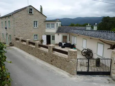 a stone house with a fence and a driveway at Casa Cástor O Valadouro Galicia in Alaje