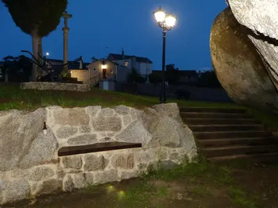 a stone bench on a stone wall at night at Casa Cástor O Valadouro Galicia in Alaje