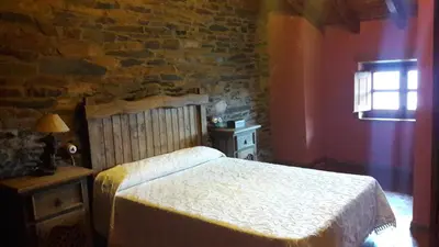 a bedroom with a bed and a brick wall at Casa rural Albina in Susañe del Sil