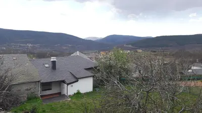 a white house with a roof with mountains in the background at Casa rural Albina in Susañe del Sil