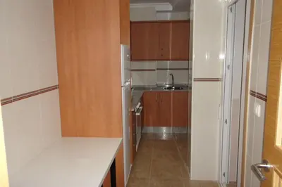 a kitchen with wooden cabinets and a refrigerator at Apartamento en 1ª línea de la Playa de Covas - Viveiro (Lugo) in Viveiro