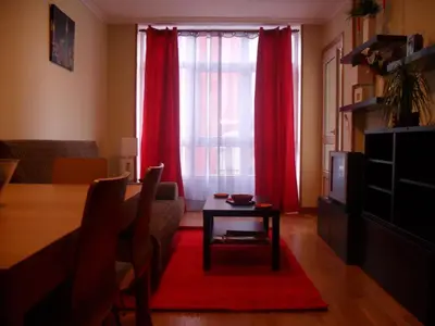 a living room with a table and red curtains at Apartamento en 1ª línea de la Playa de Covas - Viveiro (Lugo) in Viveiro