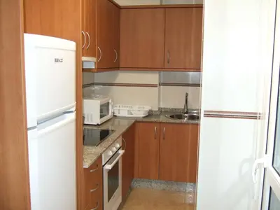 a kitchen with wooden cabinets and a white refrigerator at Apartamento en 1ª línea de la Playa de Covas - Viveiro (Lugo) in Viveiro