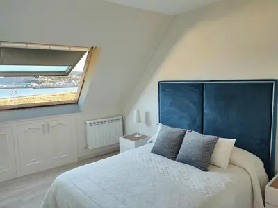 a bedroom with a large bed with a blue headboard at Perla del Cantábrico in Vivero