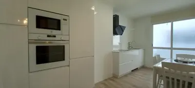 a white kitchen with a microwave and a table at Perla del Cantábrico in Vivero
