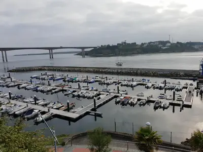 a group of boats docked in a marina with a bridge at Apartamentos O Cargadeiro Ribadeo in Ribadeo