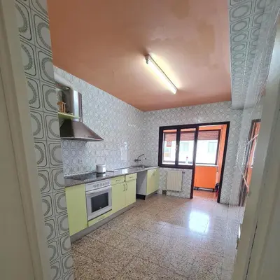 a kitchen with yellow cabinets and a stove top oven at Apartamentos O Cargadeiro Ribadeo in Ribadeo