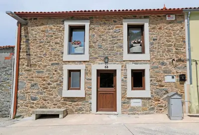 a stone building with two windows and a door at Casa Santa María in Melide
