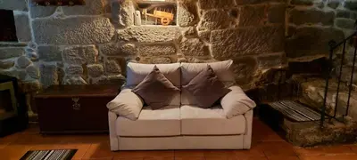 a white couch with pillows sitting in a room with a stone wall at Casa da Canella - En la Ribeira Sacra in Ourense