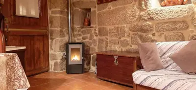 a living room with a stone wall with a fireplace at Casa da Canella - En la Ribeira Sacra in Ourense