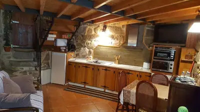 a kitchen with wooden cabinets and a table and a couch at Casa da Canella - En la Ribeira Sacra in Ourense