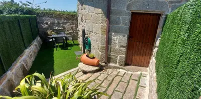 a small garden with a wooden door and a table at Casa da Canella - En la Ribeira Sacra in Ourense