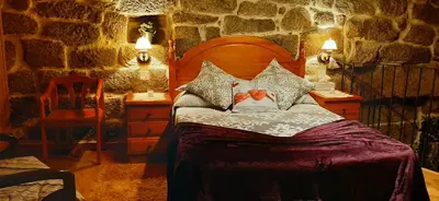 a bedroom with a bed and a stone wall at Casa da Canella - En la Ribeira Sacra in Ourense