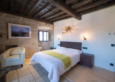 a bedroom with a large bed and a chair at Reitoral de Parada in Parada del Sil