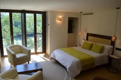 a bedroom with a bed and a chair and windows at Reitoral de Parada in Parada del Sil